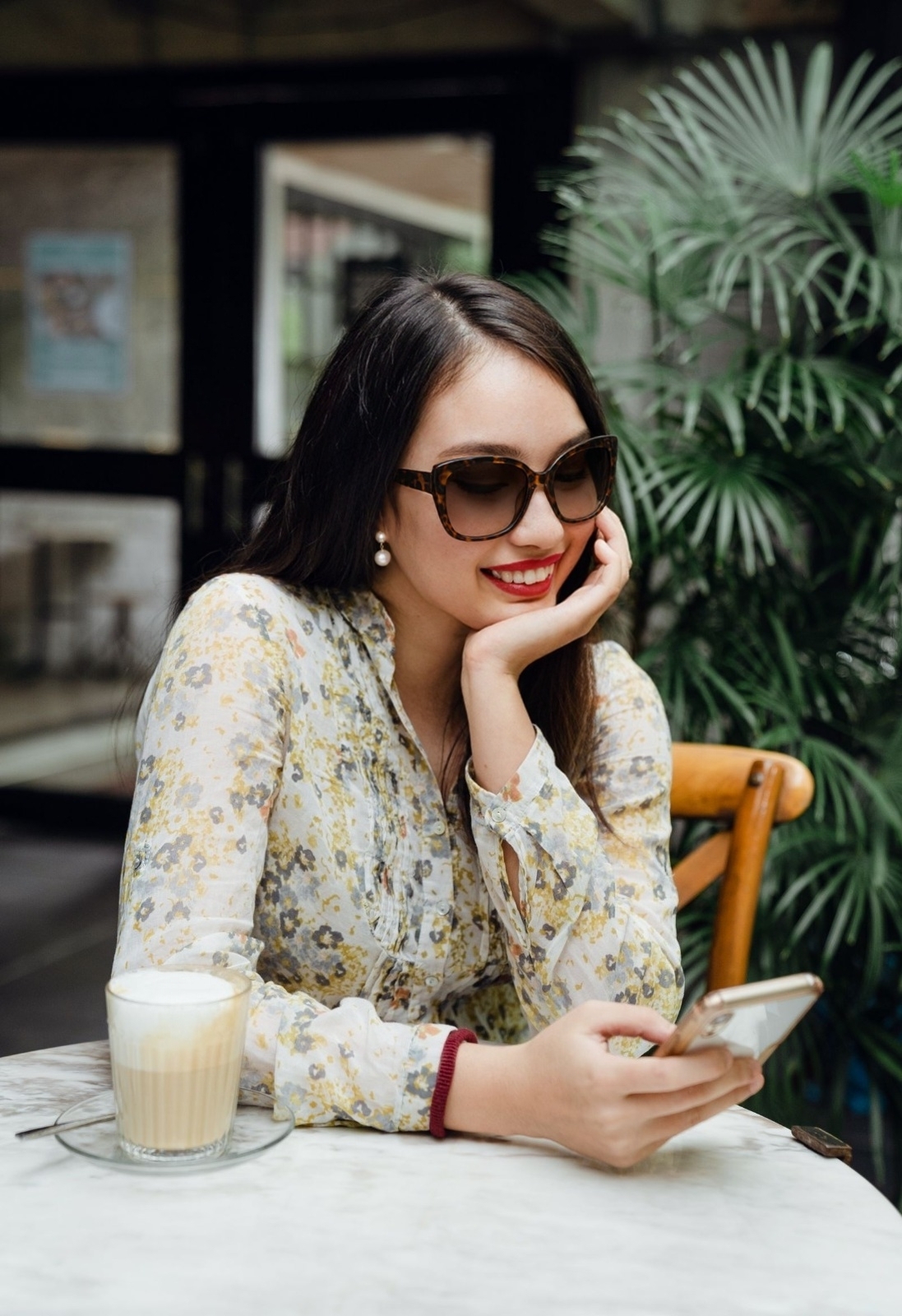 Creator smiling at her phone while working from a softly lit café